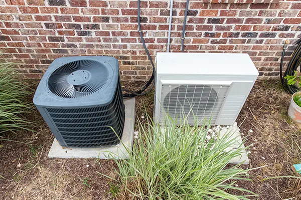 Ductless mini-split system next to a traditional AC unit