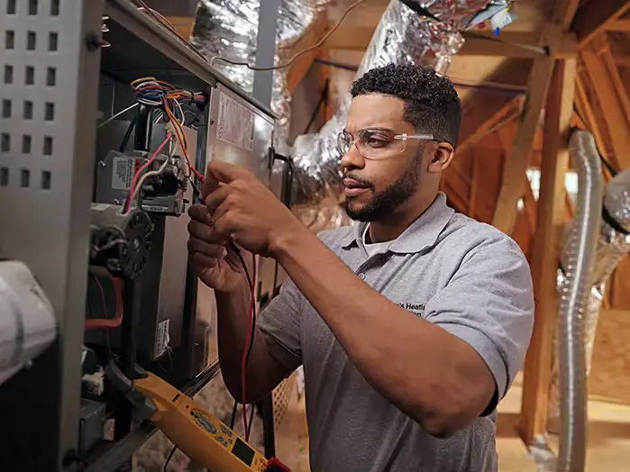 Repairman working on a furnace in an attic