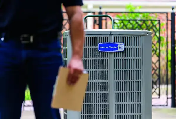 Maintenance technician standing next to an American Standard heating unit