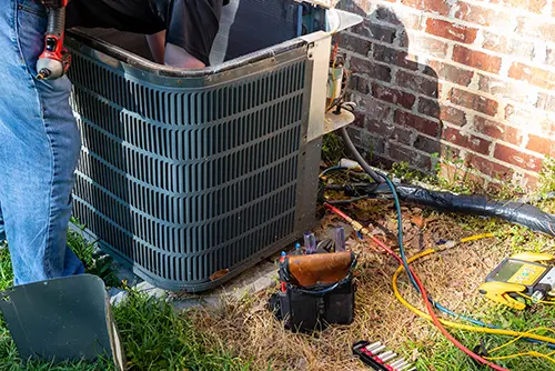 An outdoor heating unit being repaired by a technician